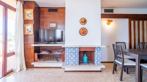 A living room with a fireplace, television, and dining area. - Cubo's Playamar Beach Apartment / communal pool / terrace / air conditioning / free Wi-Fi (Torremolinos)