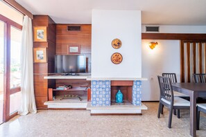 A living room with a fireplace, television, and dining area. - Cubo's Playamar Beach Apartment / communal pool / terrace / air conditioning / free Wi-Fi (Torremolinos)