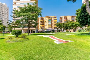 A residential area with multi-story apartment buildings, a well-maintained grassy lawn, and a pathway. - Cubo's Playamar Beach Apartment / communal pool / terrace / air conditioning / free Wi-Fi (Torremolinos)