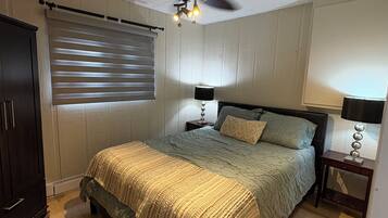 A bedroom with a bed, a ceiling fan, a window with blinds, and a wardrobe.
