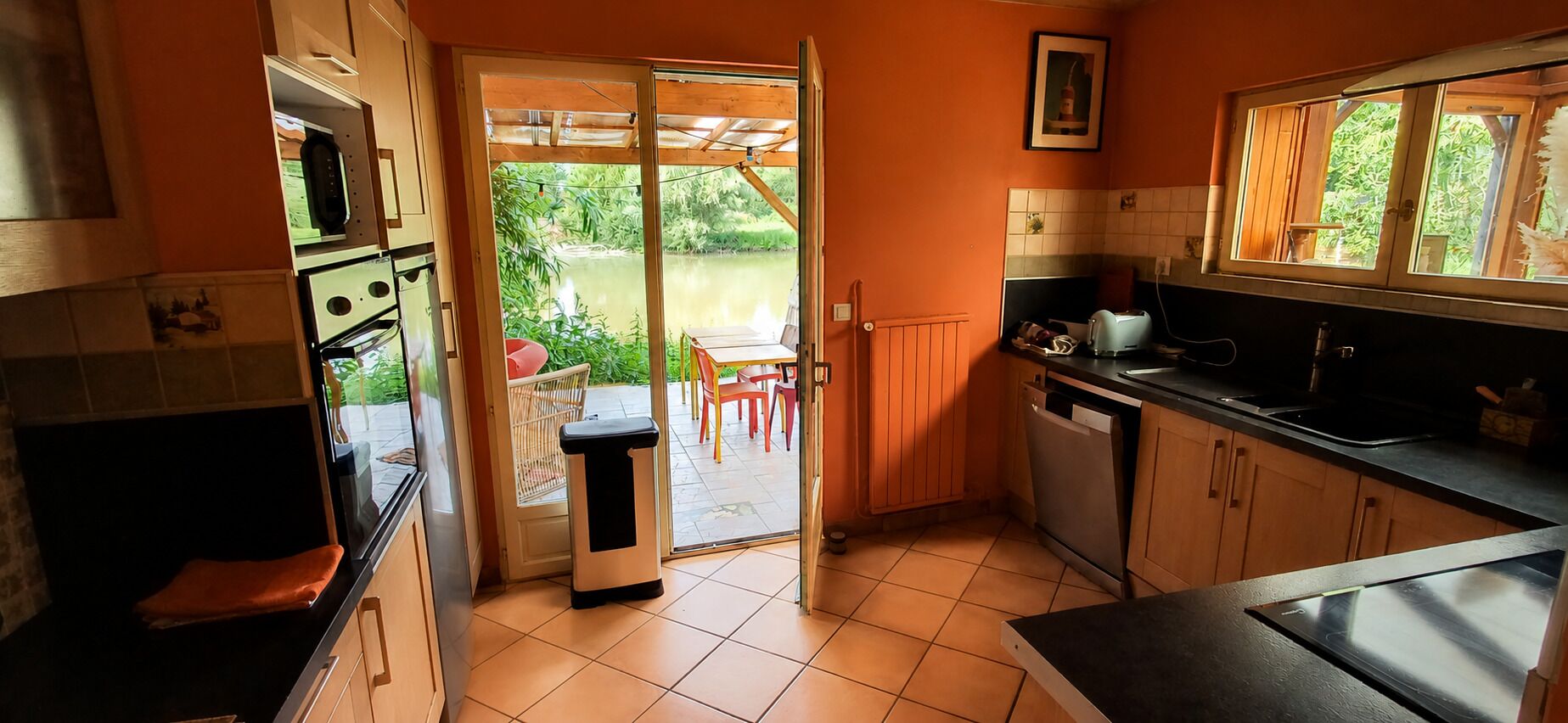A kitchen with a sliding glass door leading to an outdoor area with a table and chairs.