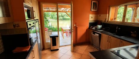 Una cocina con puerta corrediza de vidrio que da a un espacio exterior con mesa y sillas.