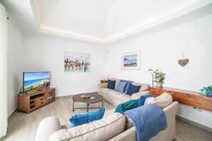 Ein Wohnzimmer mit Fernseher, Sofa, Couchtisch und Kunstwerken an den Wänden.