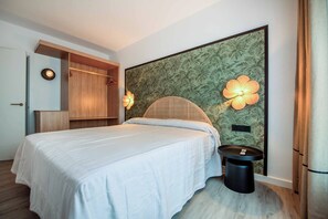 Een slaapkamer met een bed, nachtkastje, kledingkast en een bloemen behangen muur.