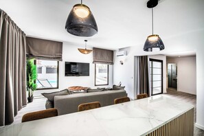 Um espaço moderno para relaxar, com sofá, mesa de jantar e luminárias pendentes.