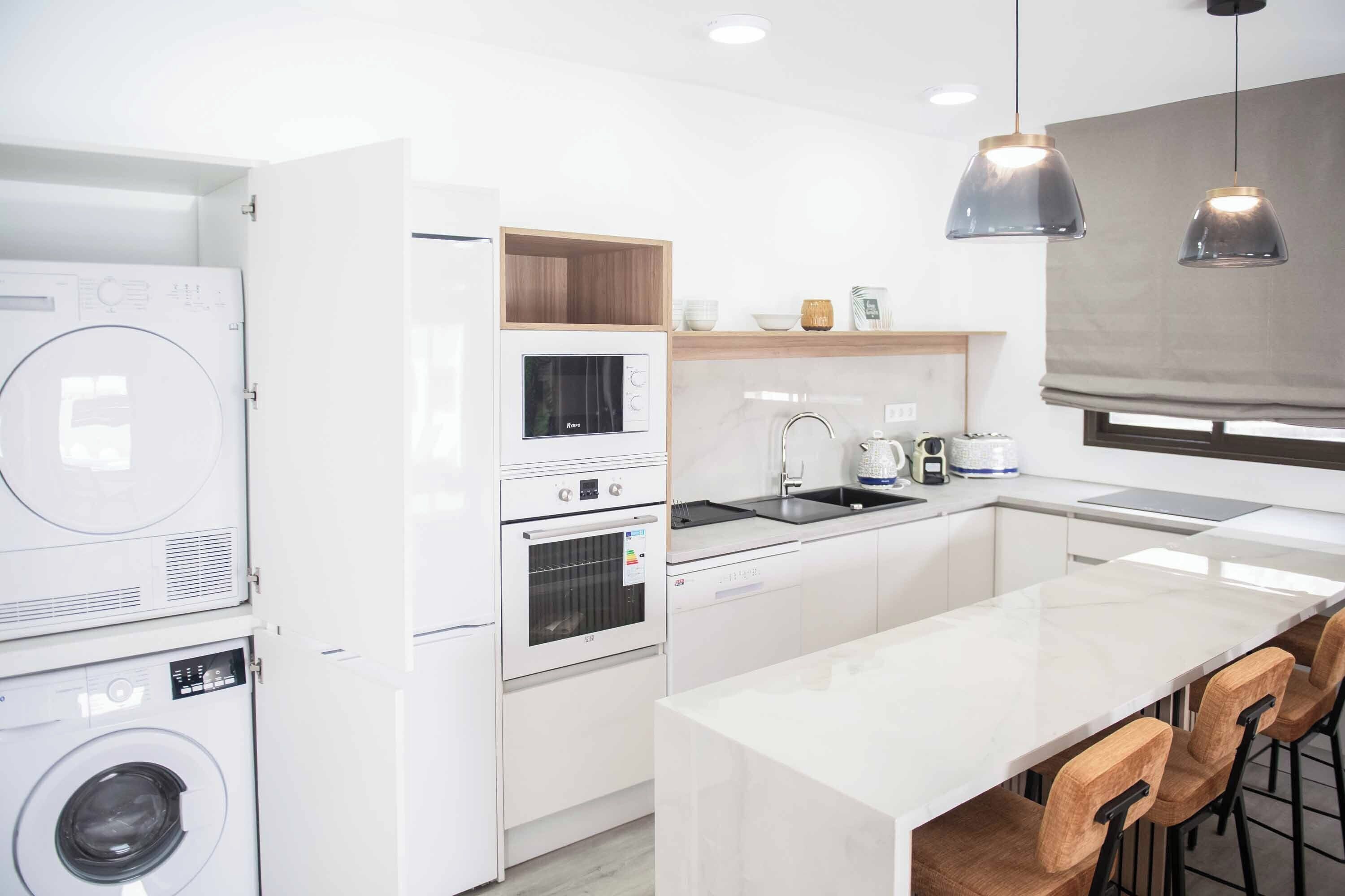 A modern kitchen with built-in appliances, a central island, and pendant lighting.