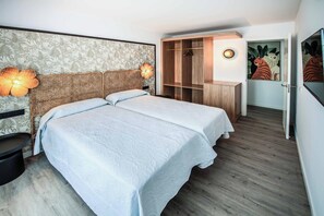 A bedroom with a bed, bedside tables, a wardrobe, and a wall with a tropical wallpaper. - Villa Orchilla - Three Bedroom Villa, Sleeps 6 (Caleta de Fustes)