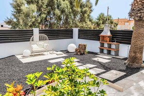 A rooftop garden with a seating area, a grill, and a decorative tree stump.