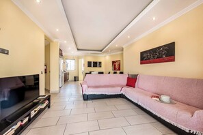 Ein Wohnzimmer mit Fernseher, Sofa und Kunstwerken.