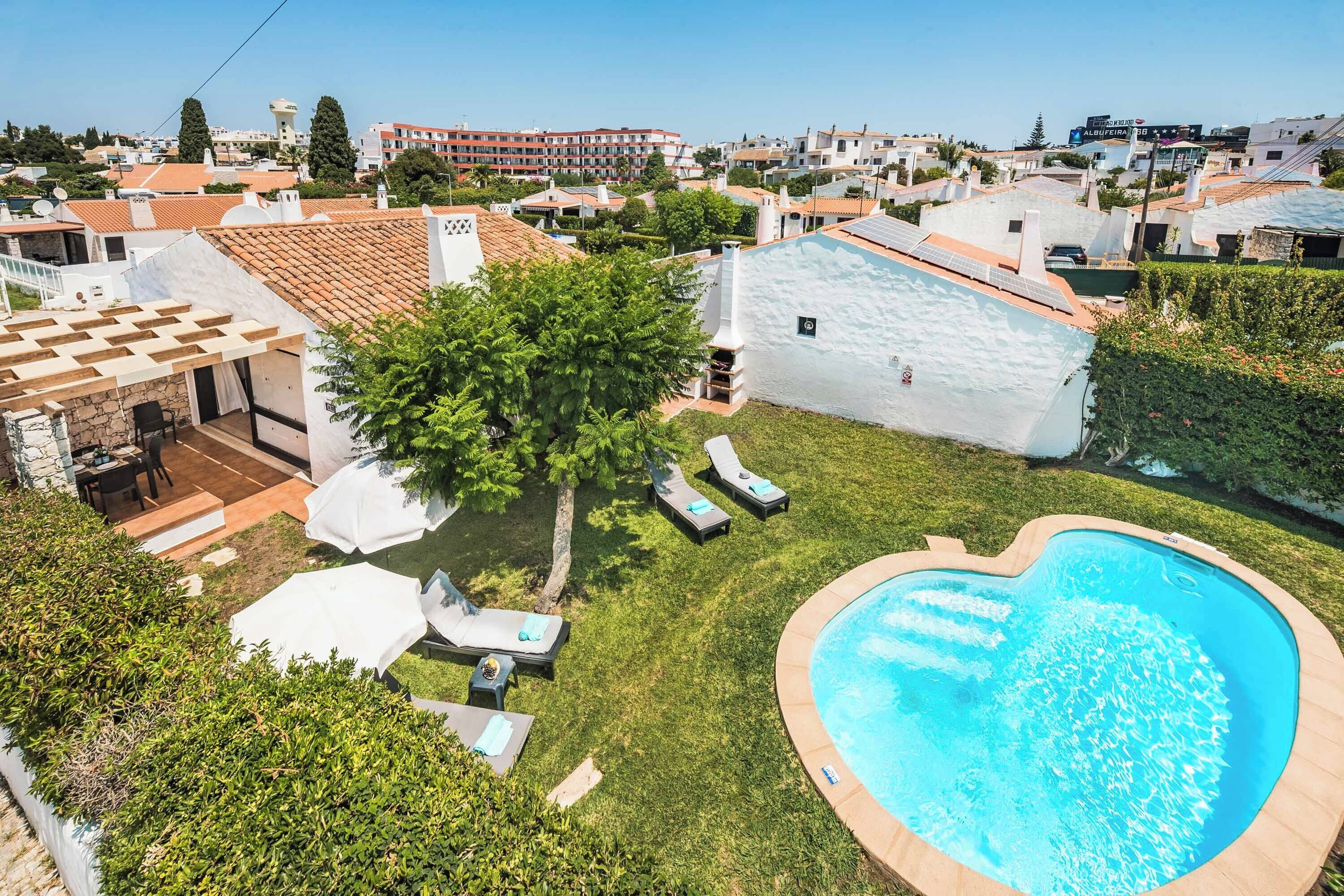 A residential property with a swimming pool, a patio with lounge chairs, and a garden area.