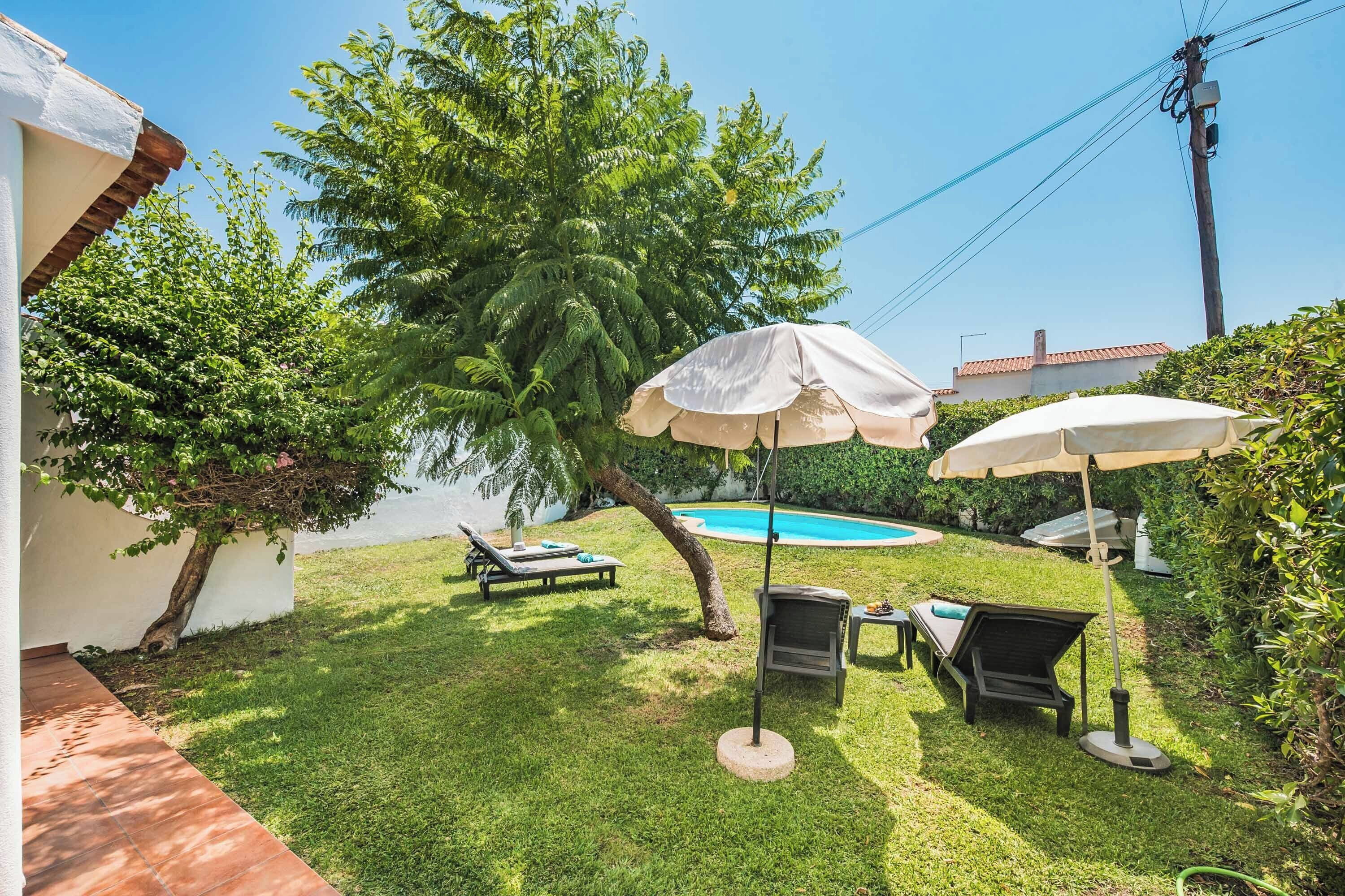A backyard with a swimming pool, two lounge chairs, and two umbrellas.