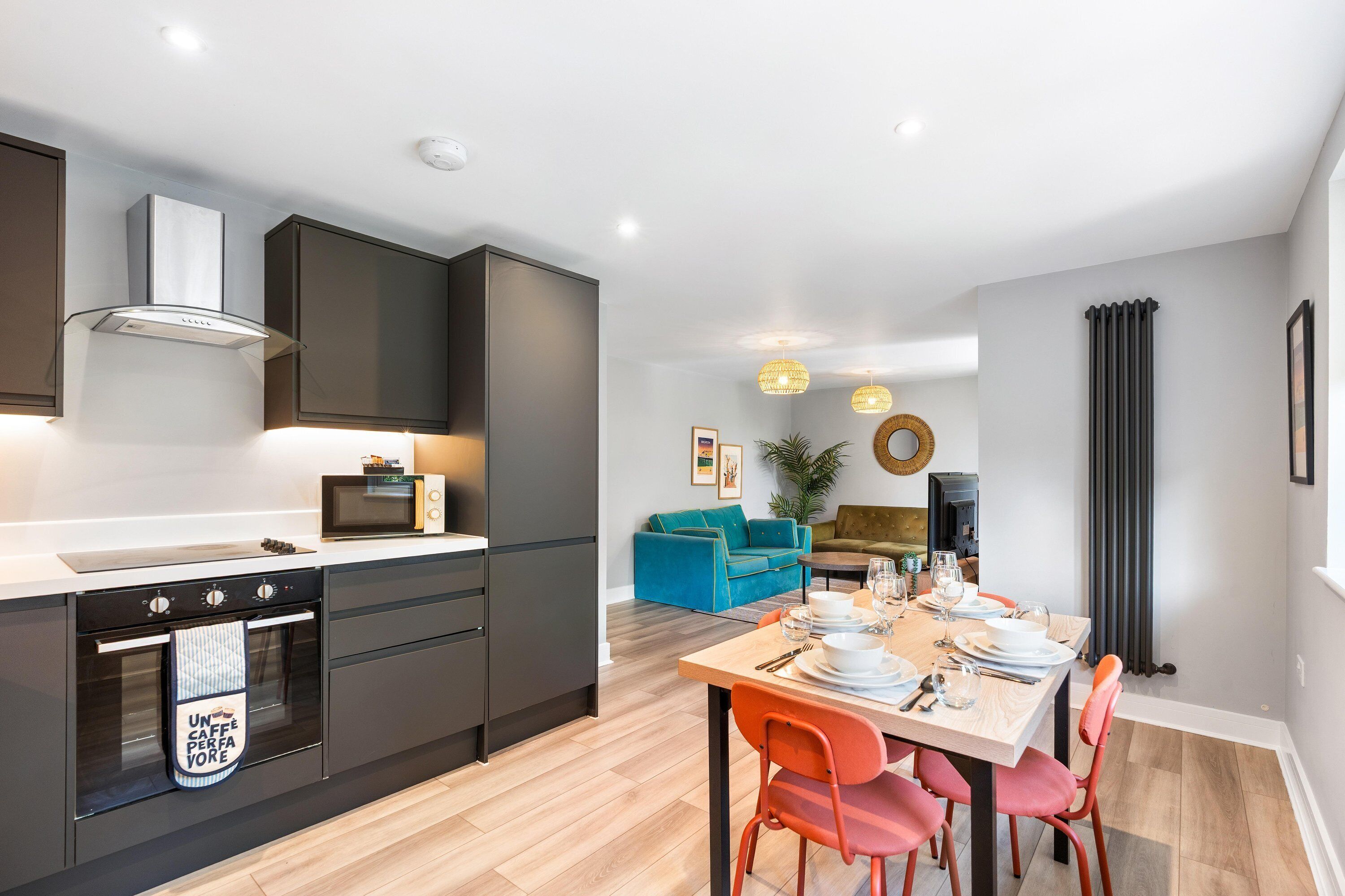A modern kitchen with built-in appliances and a dining area with a wooden table and chairs.