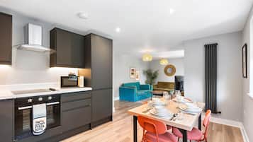 A modern kitchen with built-in appliances and a dining area with a wooden table and chairs.