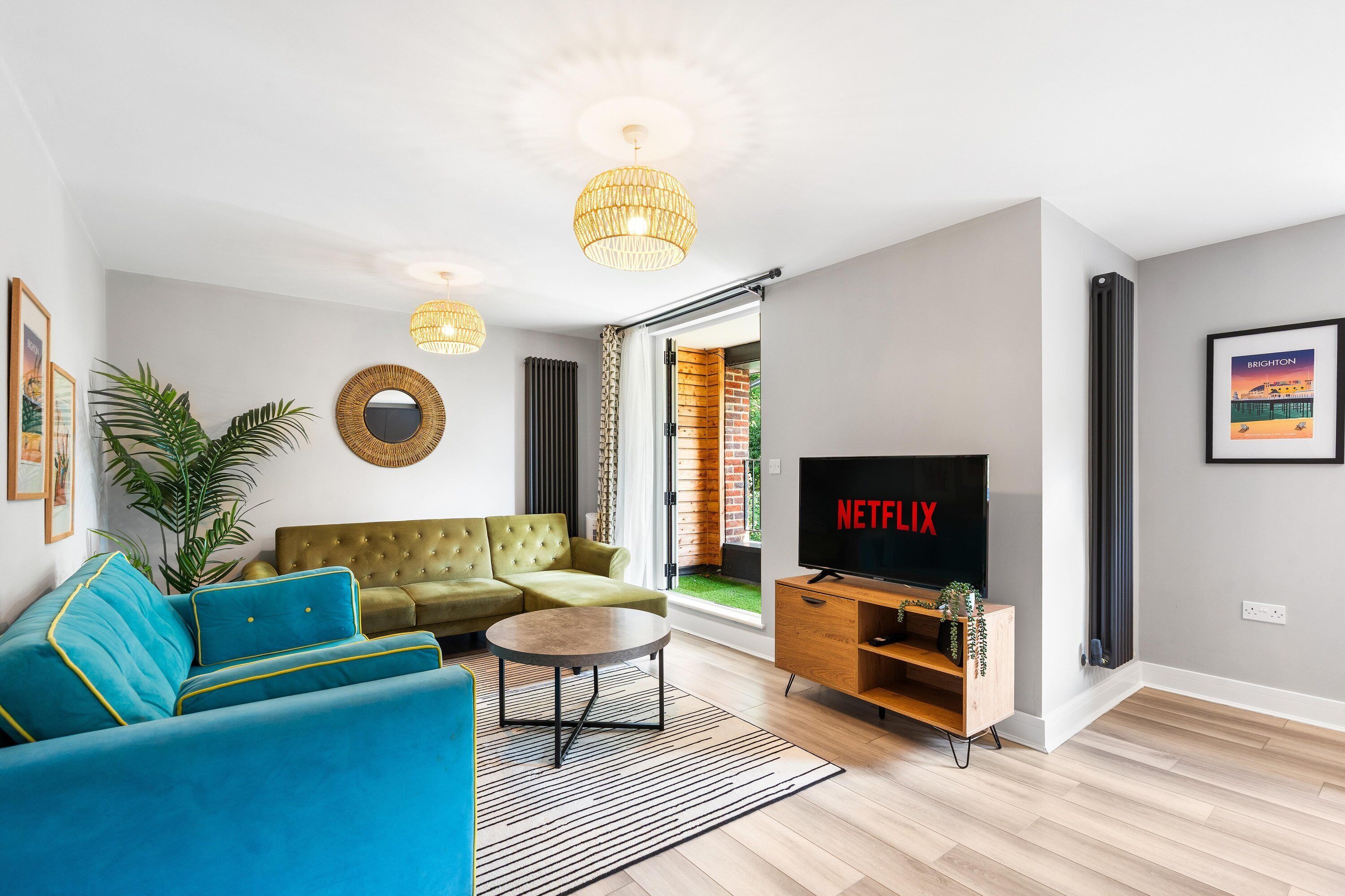 A modern living room with a sectional sofa, a coffee table, a TV, and a large window.