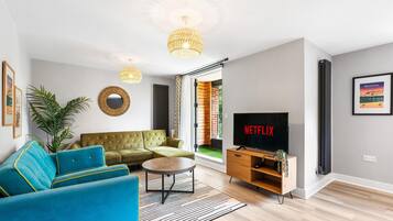 A modern living room with a sectional sofa, a coffee table, a TV, and a large window.
