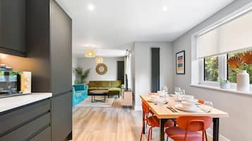 A modern kitchen with a dining area, a green sofa, and a window with a view.