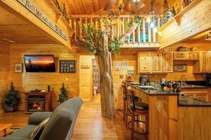 Ein gemütliches Blockhaus-Interieur mit Kamin, Holzwänden, einer Bar und einem an der Wand befestigten Fernseher.