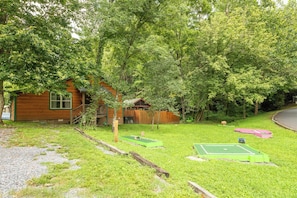A wooden cabin with a green tennis court and a small green table tennis table. - Creekview Cabin with Treehouse Loft (Sevierville)