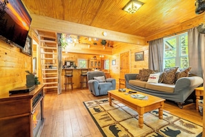 A cozy log cabin interior with a living room, kitchen, and a fireplace. - Creekview Cabin with Treehouse Loft (Sevierville)