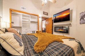 Ein Schlafzimmer mit einem Bett, einem an der Wand montierten Fernseher und einem Kleiderschrank.