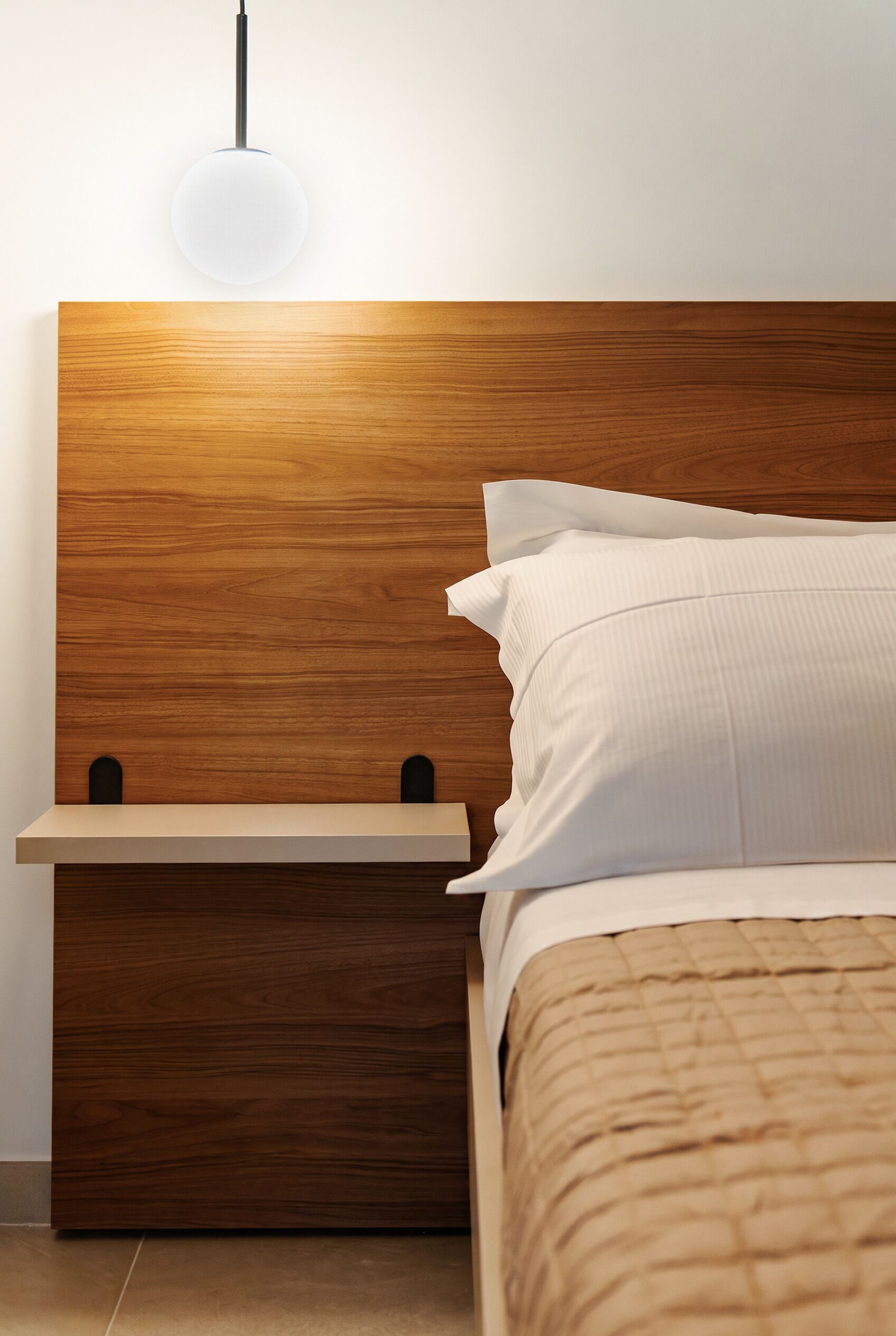 Una camera da letto moderna con una testiera in legno, un comodino e un letto con biancheria bianca.