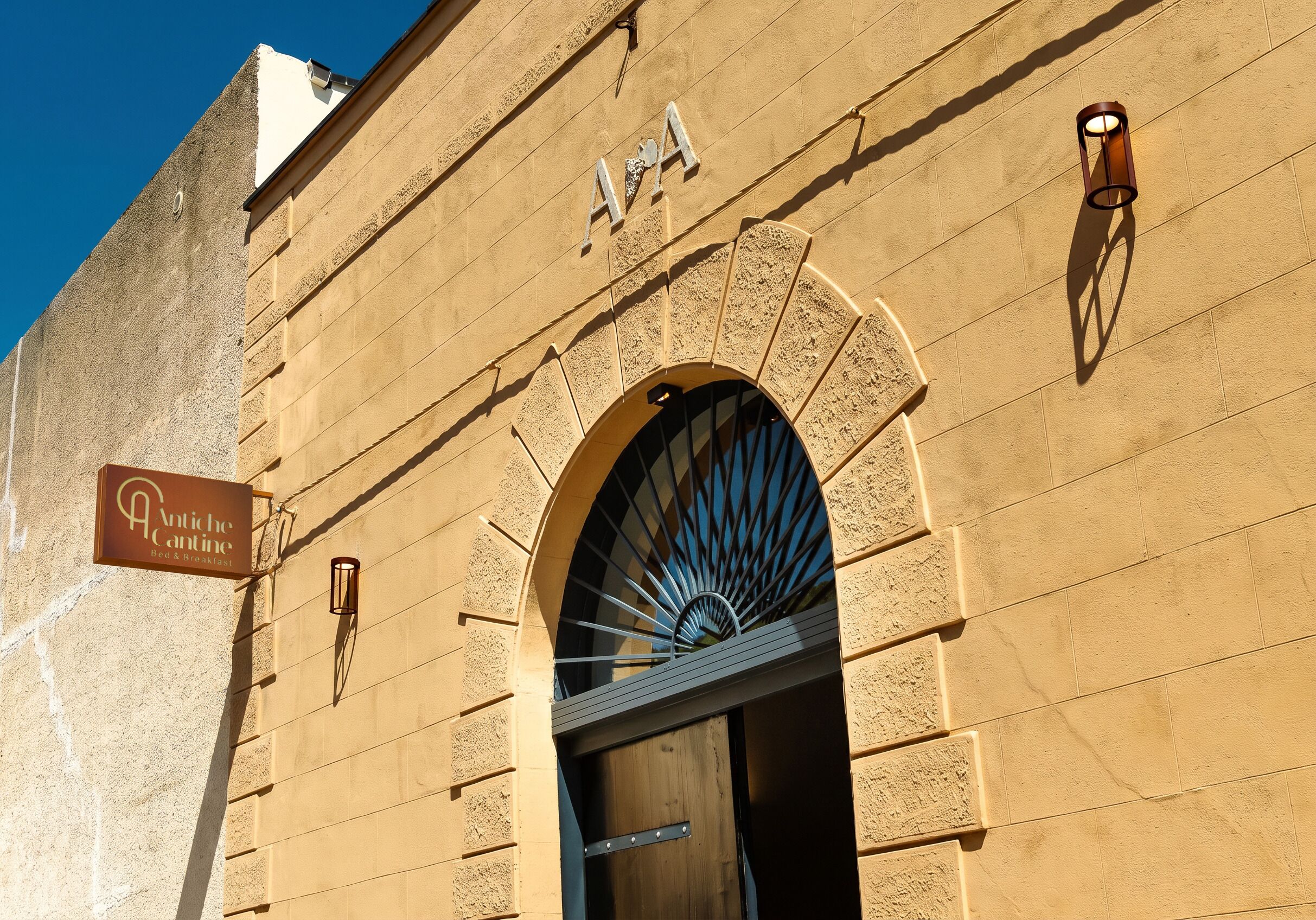 La façade d’un immeuble, ornée d’une enseigne indiquant « Antiche Cantine Bed & Breakfast », et dotée d’une grande entrée en arc de cercle.