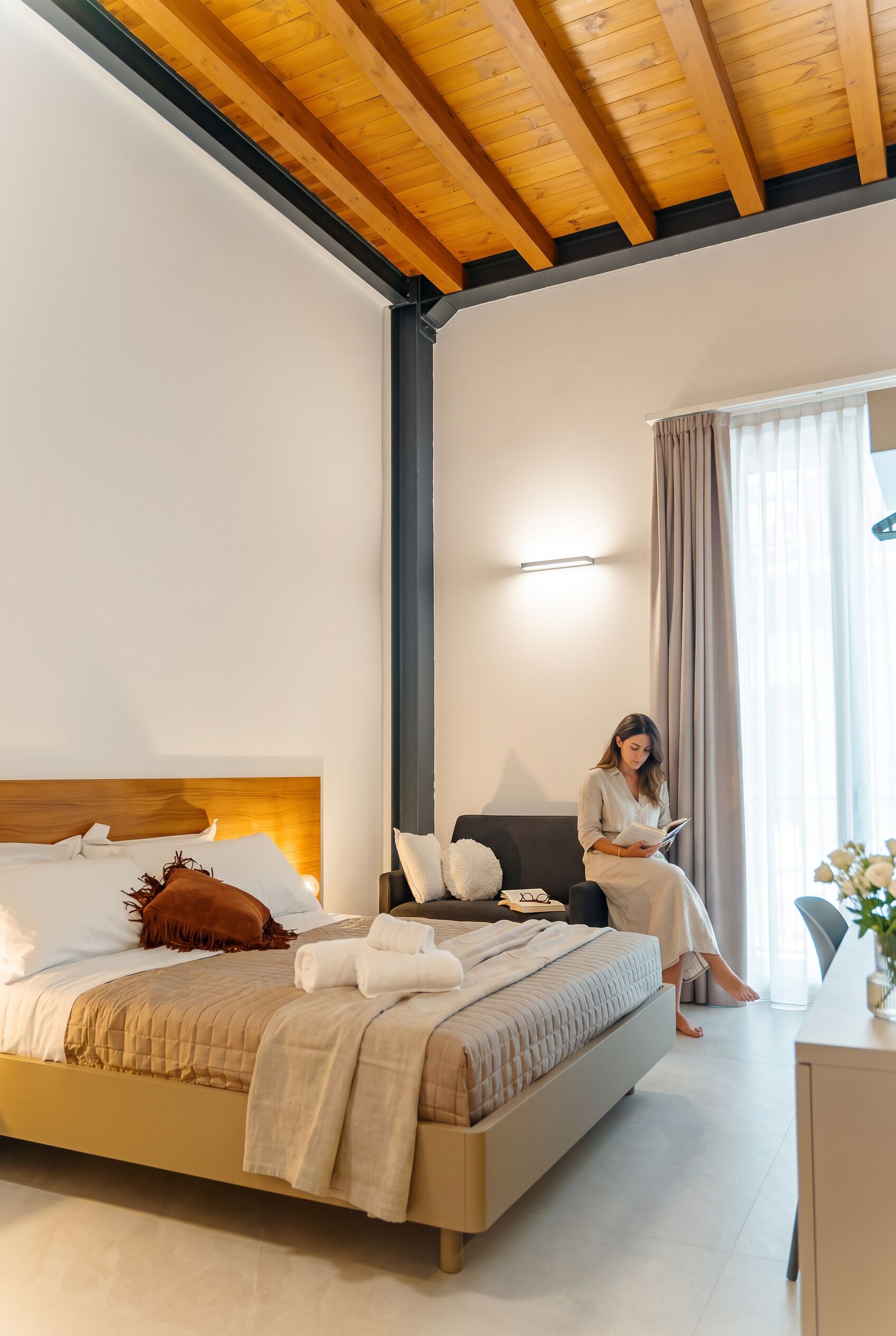 Un dormitorio moderno con cama, un sillón de lectura y un escritorio.