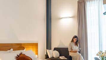 Un dormitorio moderno con cama, un sillón de lectura y un escritorio.