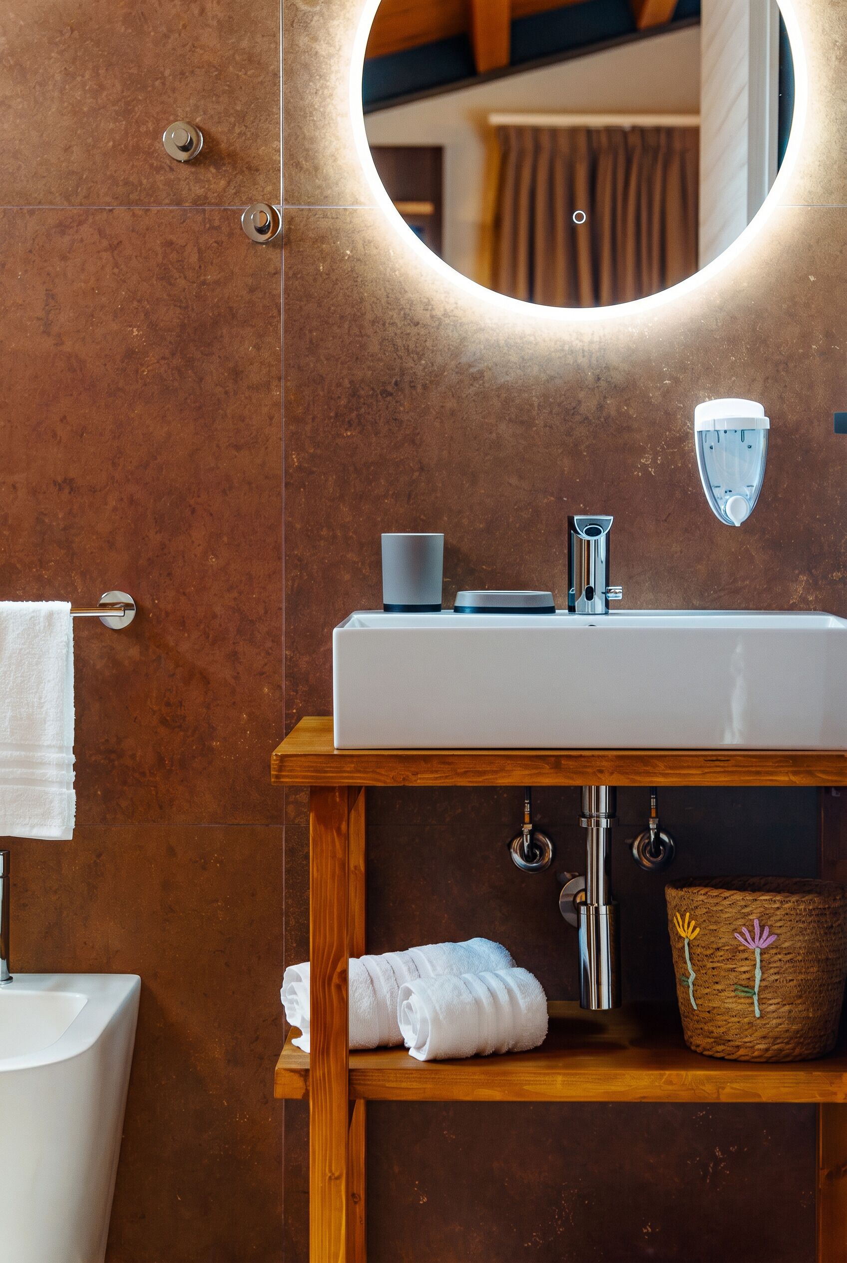 Un baño con tocador de madera, un lavabo blanco, un espejo y un perchero para toallas.