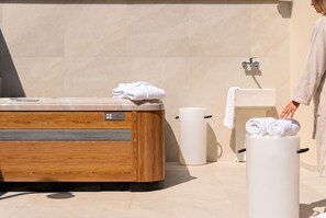 Un baño moderno con una bañera de madera, inodoro y dispensador de toallas.