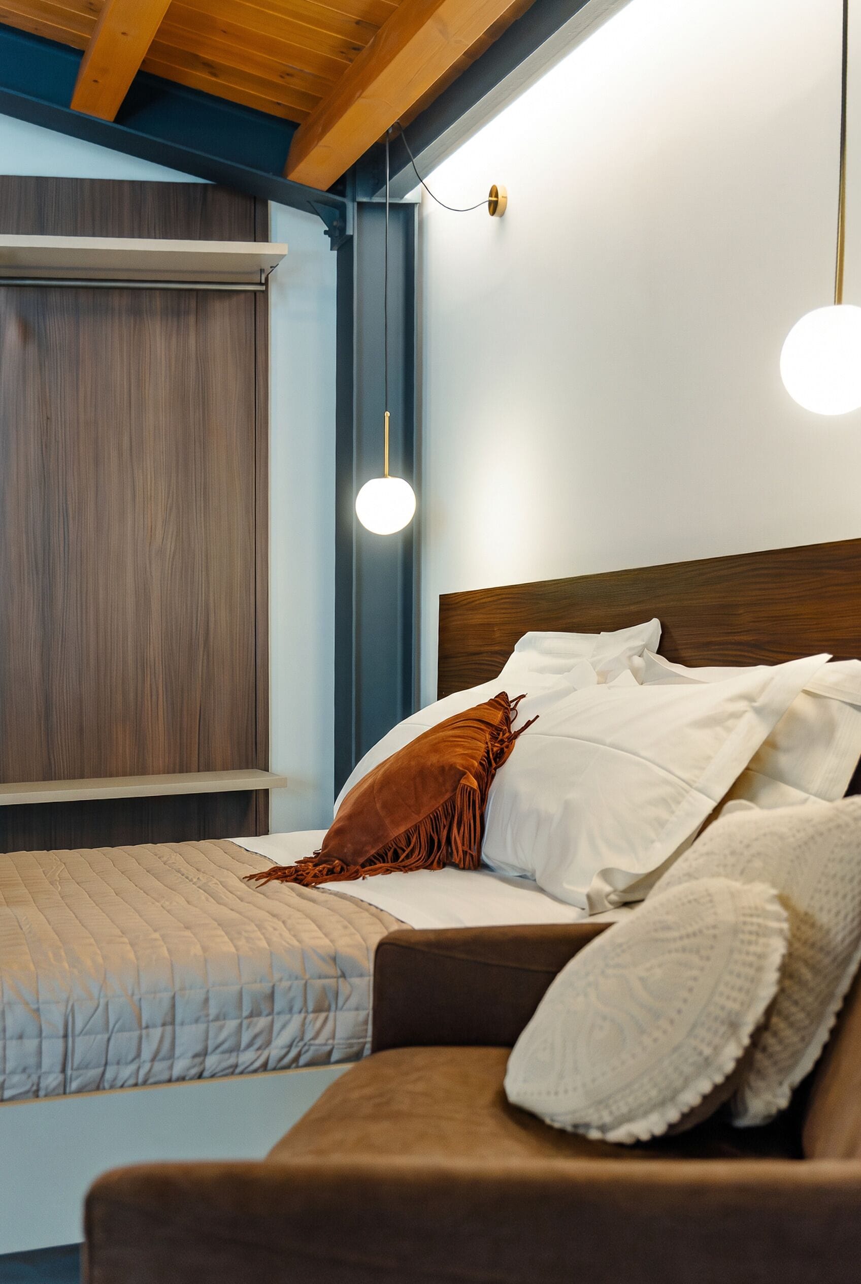 Un dormitorio con cama, mesita de noche, lámpara colgante y ventana con persianas.