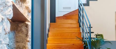 Un comedor con una escalera de madera que sube a una habitación blanca.
