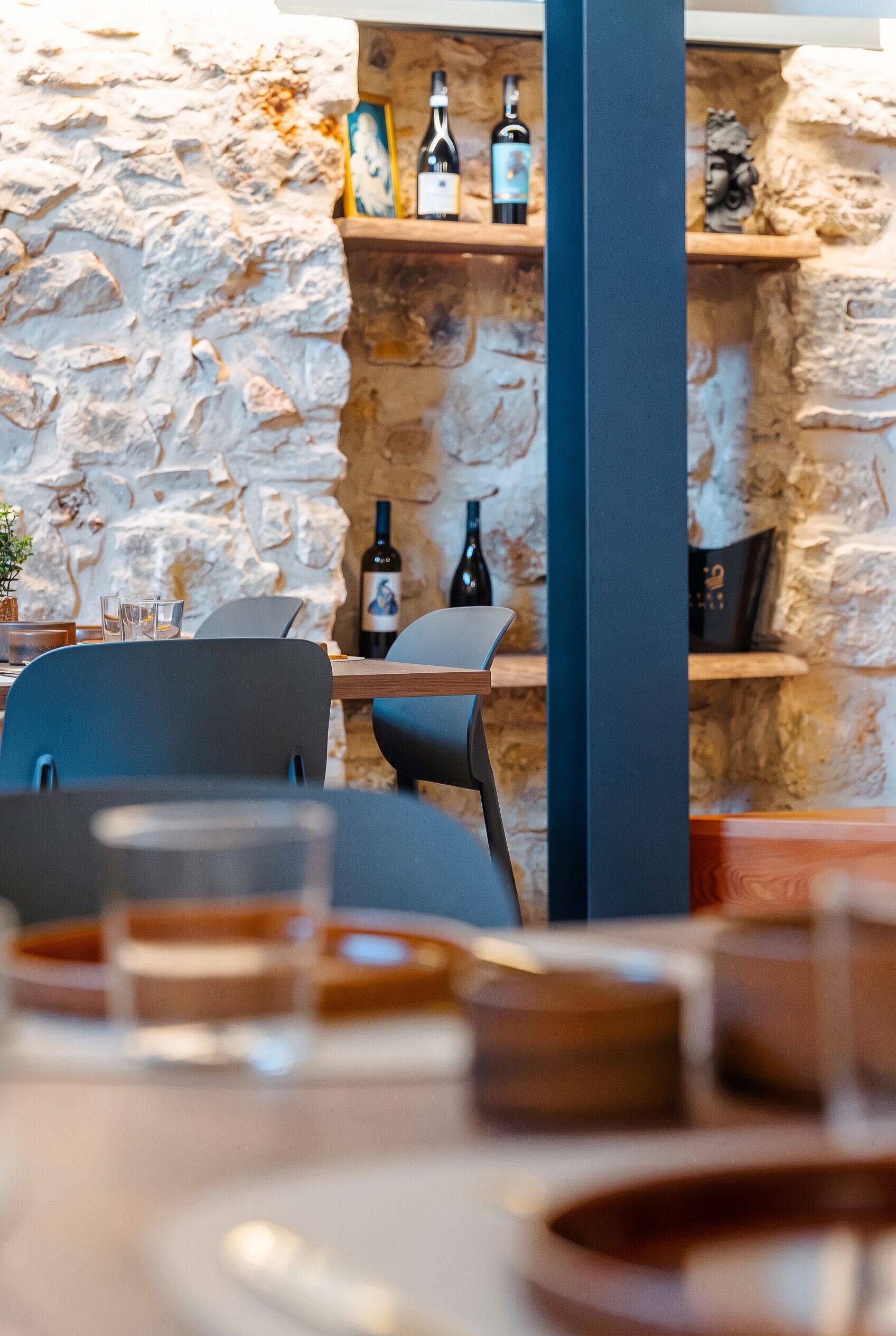 Ein Restaurantinneres mit Stehwänden, Holzmöbeln und Weinflaschen auf Regalen.