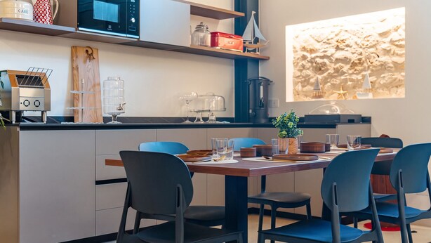 Una cocina moderna con microondas integrado, cafetera y dispensador de agua.