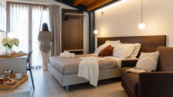 A modern bedroom with a bed, bedside table, and a seating area with a couch.