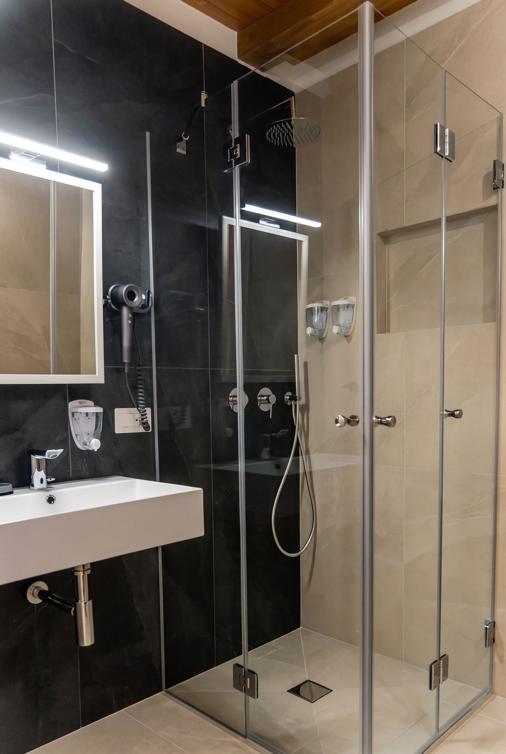 Un baño moderno con ducha envuelta en vidrio, tocador con espejo y ducha de mano.