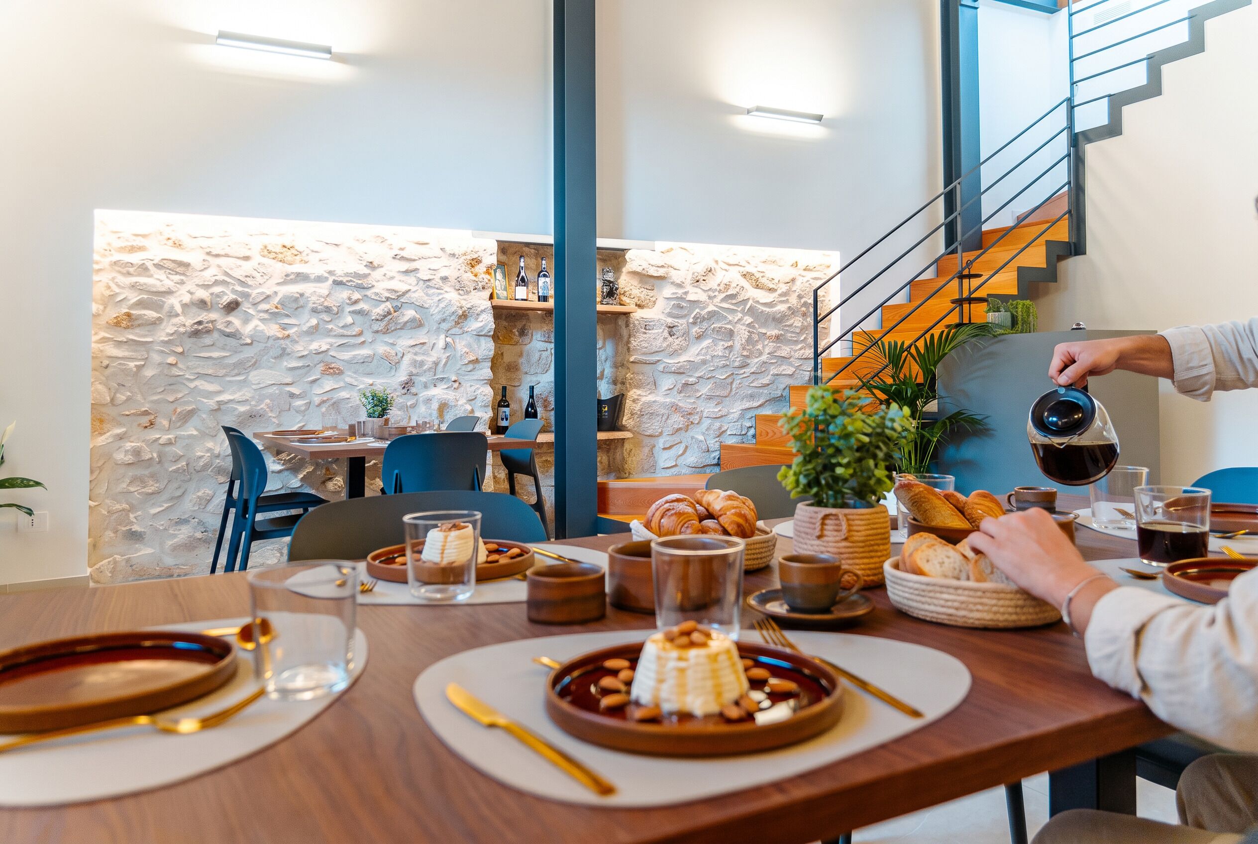 Un espace repas avec un mur en pierre, des meubles en bois et un escalier.
