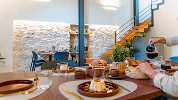 Un espace repas avec un mur en pierre, des meubles en bois et un escalier.