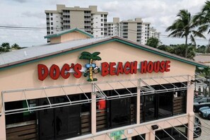 Ein Gebäude mit einem Schild, auf dem 'Doc's Beach House' steht, und einem Palmen-Logo.