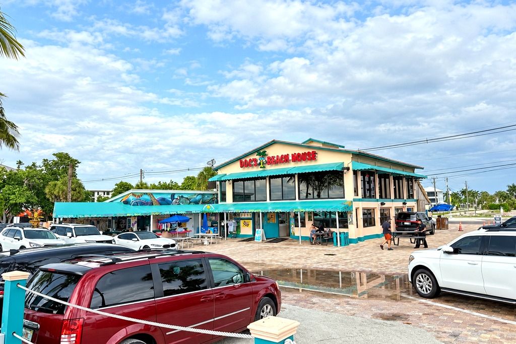 Une maison de plage avec une pancarte, un parking et un ciel dégagé.