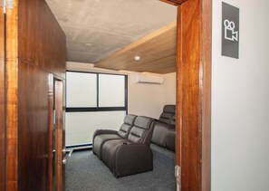 A room with a ceiling fan, a window with blinds, and a pair of leather recliners. - Corporate Stays First del Sol - 201 (Asunción)