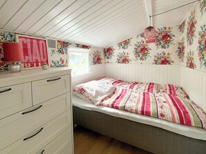 A bedroom with a bed, a dresser, and floral wallpaper. - Stay in" Sandersvig delight" filled with colours (Haderslev)