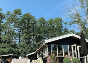 A cabin with a sloped roof, large windows, and a covered outdoor seating area. - Stay in" Sandersvig delight" filled with colours (Haderslev)