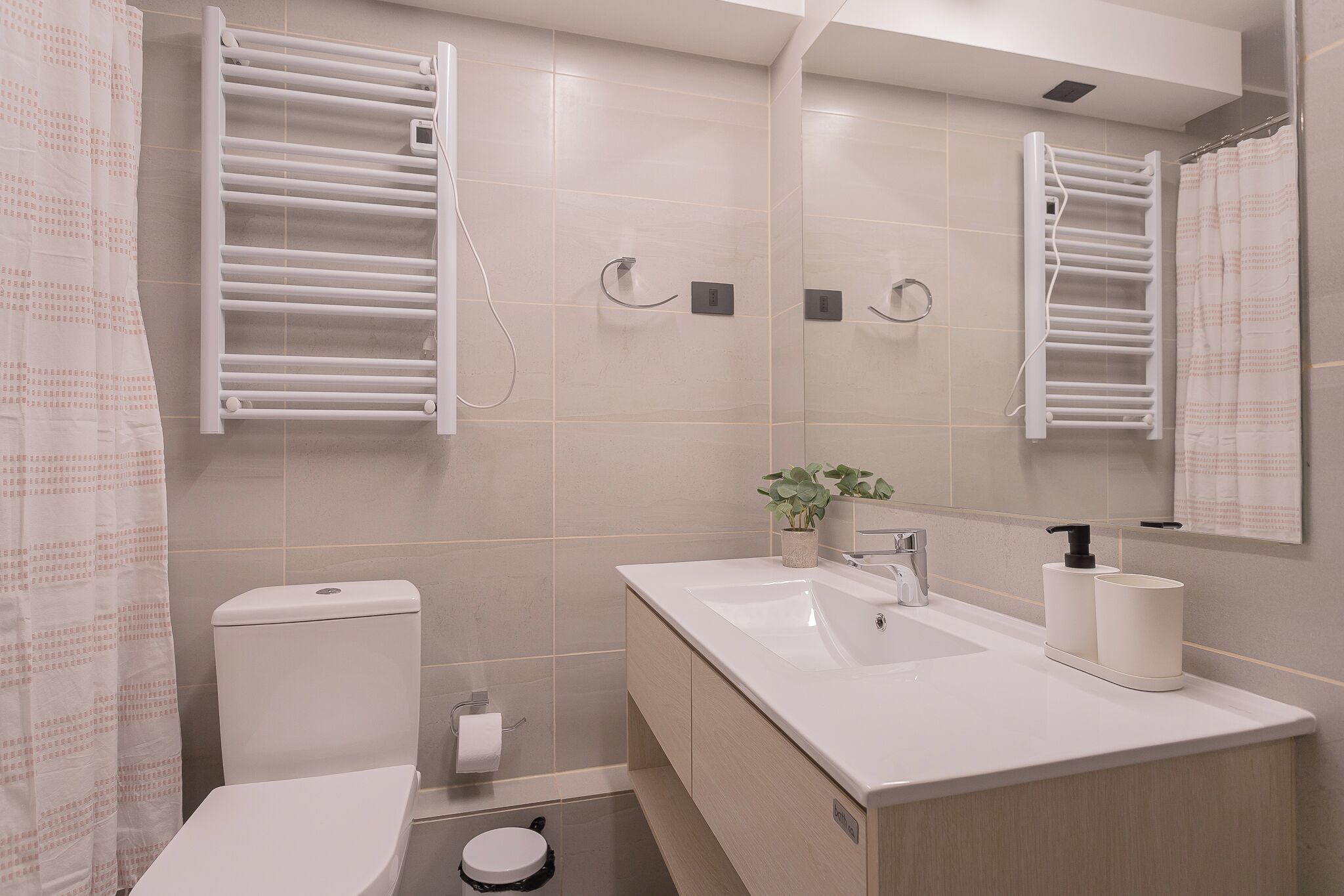 Une salle de bain moderne équipée de toilettes, d’un bidet, d’un lavabo et de porte-serviettes.