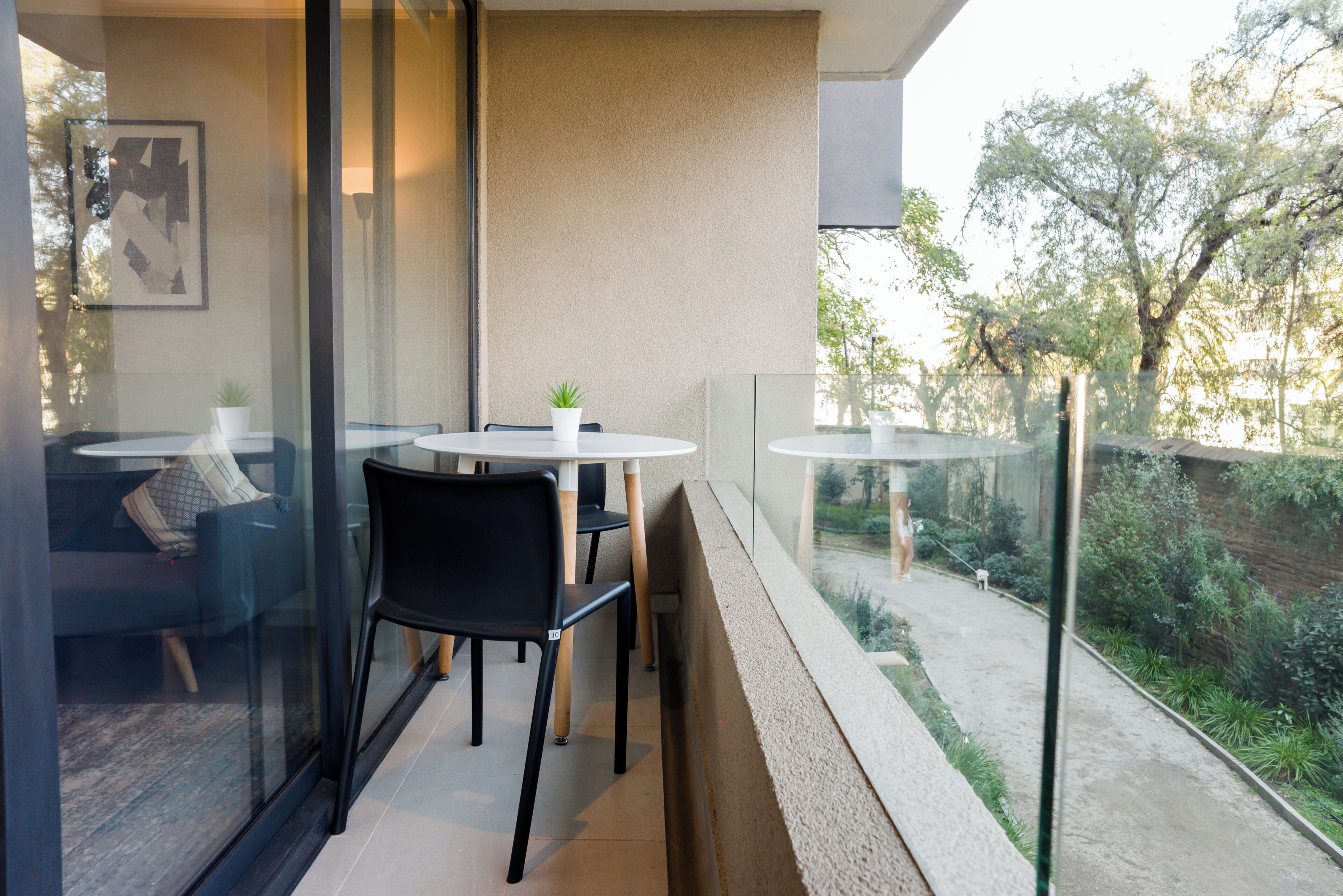 A balcony with a glass railing, two tables, and chairs.