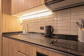 Eine moderne Küche mit schwarzem Arbeitsplatz, Holzschränken, einem Edelstahlkocher und einem Geschirrgestell.