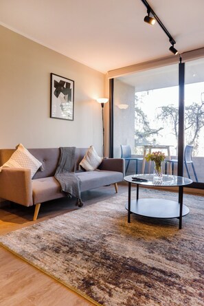 A modern living room with a sofa, a coffee table, and a large window.