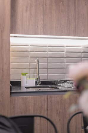 A kitchen with wooden cabinets, a stainless steel sink, and a tiled backsplash.