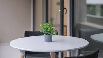 A round table with a small potted plant, black chairs, and a glass partition.
