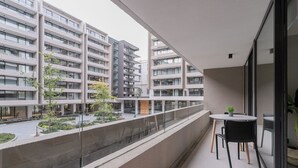 A balcony with a table and chairs, overlooking a modern building complex. - Pedro Valdivia Apartments by Andes STR (Providencia)